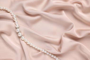 Üstten görünen bej kumaşlı zarif inci kolye. Metin için boşluk