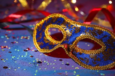 Beautiful carnival mask, ribbons and confetti on color background, closeup clipart