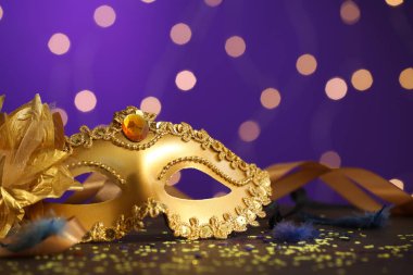 Renkli arka planda güzel bir karnaval maskesi, kurdeleler ve konfeti, bulanık ışıklar, yakın plan