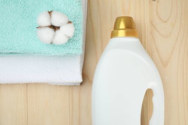 Çamaşır deterjanı şişede, pamuk çiçeği ve havlular ahşap masada, üst tarafta.