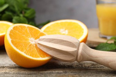 Juicer and fresh oranges on wooden table, closeup clipart