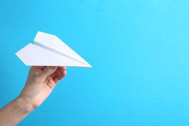 Açık mavi arka planda el yapımı kağıt uçaklı bir kadın, yakın plan. Metin için boşluk