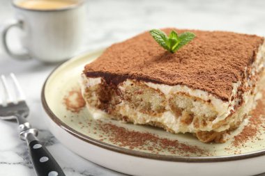 Beyaz mermer masanın üzerinde lezzetli bir tiramisu parçası, yakın plan.