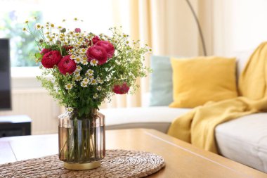 Güzel ranunculus çiçekleri ve vazolar içerideki masada.