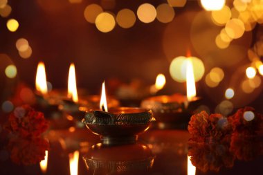 Diwali kutlaması. Diya lambaları ve arka planda güzel çiçekler, yakın plan. Bokeh etkisi