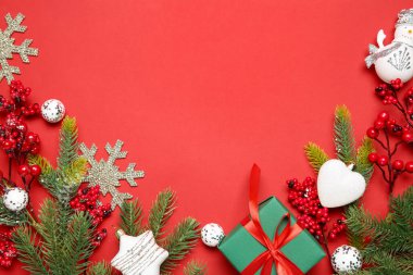 Kırmızı arka planda Noel dekoru ve hediye kutusu olan düz bir kompozisyon. Metin için boşluk