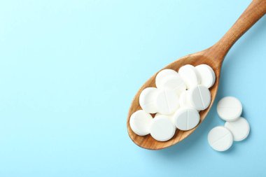 Antibiyotik haplar ve açık mavi arka planda kaşık. Metin için boşluk