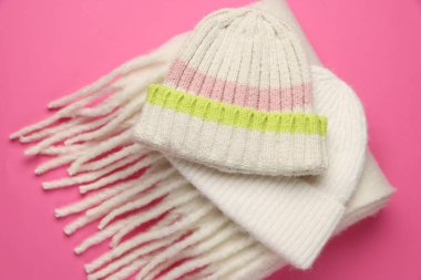 Pembe arka planda sıcak yün şapkalar ve eşarp, yakın plan.