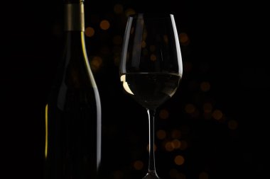 Şarap bardakta ve şişe siyah arkaplanda, yakın plan.