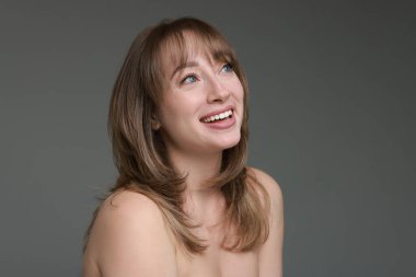 Gri arka planda şık saç kesimi olan çekici bir kadın.