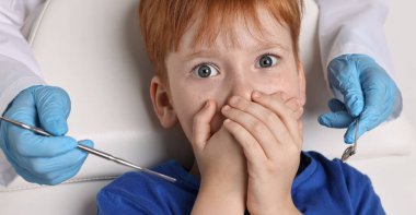 Dental phobia. Dentist working with scared little boy clipart