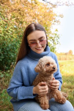 Dışarıda sevimli köpeğiyle gülümseyen kadın.