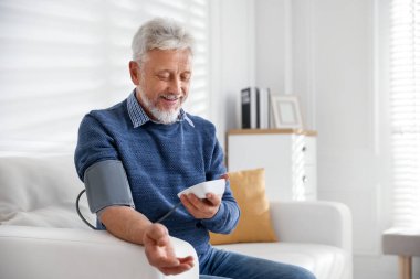 İçerideki koltukta kan basıncını ölçen yaşlı bir adam.