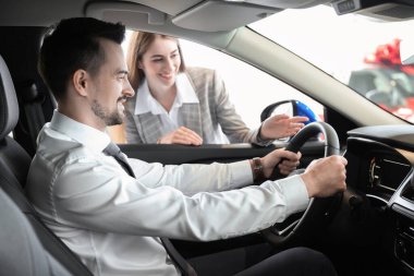 Satıcı kadın salonda müşteriye araba gösteriyor.