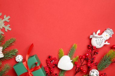 Kırmızı arka planda Noel dekoru ve hediye kutusu olan düz bir kompozisyon. Metin için boşluk
