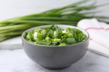 Doğranmış yeşil soğan beyaz masada, yakın plan.