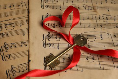 Müzik notalarında anahtar ve kalp şeklinde kurdele, yakın plan.