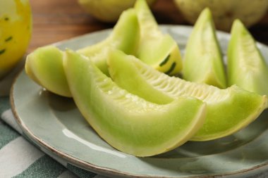 Plate with pieces of honeydew melon on table, closeup clipart