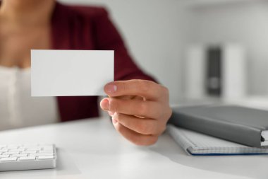 Ofisteki masada boş bir kartvizit tutan kadın, yakın plan. Tasarım için model