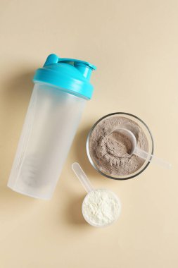 Kâsede protein tozu, bej arka planda kepçe ve titretici, düz uzanma