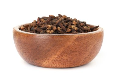 Beyaz arka planda tahta kasede kuru karanfil tomurcukları. Aromatik baharat