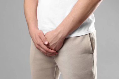 Cinsel yolla bulaşan hastalıklar. Gri arka planda semptomlardan muzdarip bir adam, yakın plan