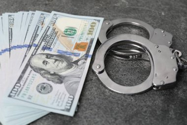 Yozlaşma konsepti. Kelepçe ve dolar banknotları gri masada, yakın plan.