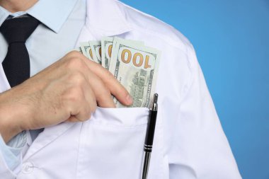 Yozlaşma konsepti. Doktor cebine dolar banknotları koyuyor mavi arka planda, yakın plan