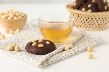 Fındıklı çikolatalı kurabiyeler ve beyaz masada çay, yakın plan.