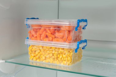 Buzdolabında farklı donmuş sebzeler olan plastik kaplar.