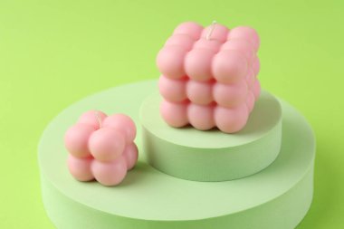 Yeşil arka planda güzel pembe baloncuk mumları ve podyumlar, yakın plan.