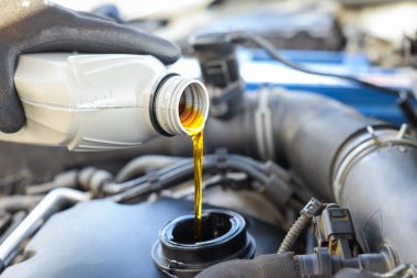 Otomobil motoruna motor yağı döken adam, yakın plan.