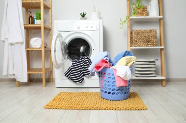 Banyoda yerde çamaşır dolu plastik bir sepet.