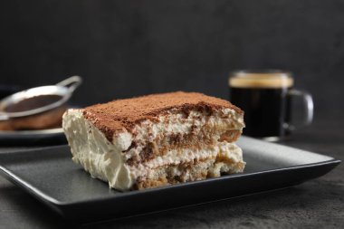 Siyah masanın üzerinde lezzetli bir tiramisu parçası, yakın plan.