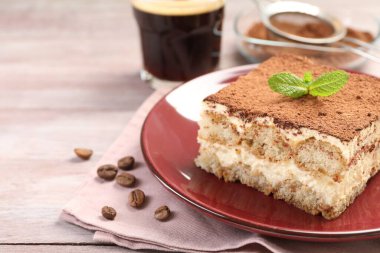 Lezzetli tiramisu tabağı, nane ve kahve çekirdekleri ahşap masada, yakın plan.