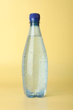 Sarı arka planda plastik su şişesi