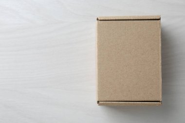 Beyaz ahşap arka planda boş bir karton kutu, üst manzara. Tasarım için model