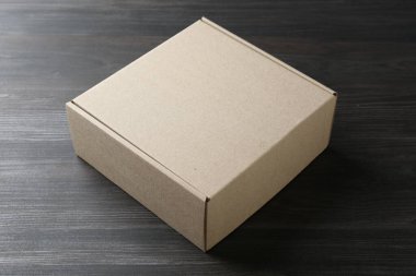 Ahşap arka planda boş bir karton kutu. Tasarım için model