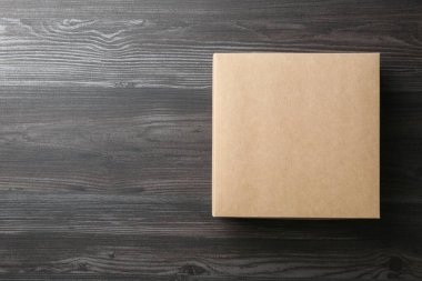 Ahşap arka planda boş bir karton kutu, üst manzara. Tasarım için model