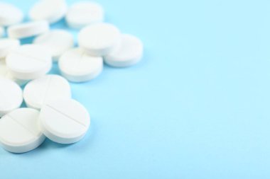 Açık mavi arka planda bir sürü antibiyotik hapı var. Yakın plan. Metin için boşluk