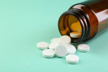 Turkuaz arka planda bir şişe antibiyotik hapı, yakın plan. Metin için boşluk