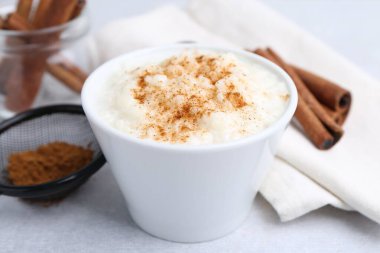 Delicious rice pudding with cinnamon on light table, closeup