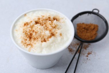 Delicious rice pudding with cinnamon on light table, closeup