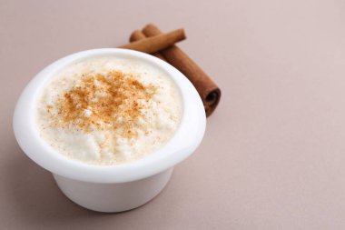 Koyu bej arka planda tarçın çubuklu lezzetli sütlaç, yakın plan. Metin için boşluk