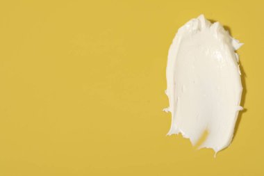 Sarı arkaplanda krem, üst görünümde ve metin için boşluk. Kozmetik ürün örneği