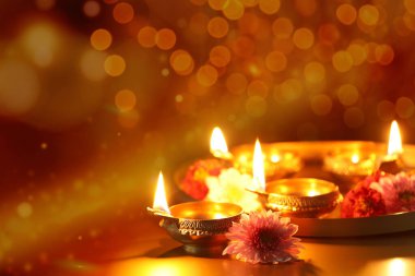 Diwali kutlaması. Diya lambaları ve arka planda güzel çiçekler, yakın plan. Mesaj için yer var. Bokeh etkisi
