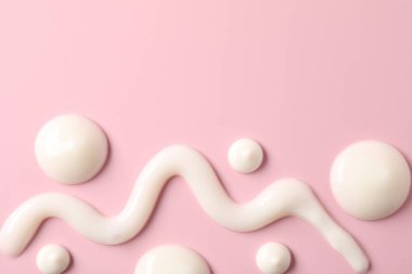 Pembe arka planda krema, düz yatak ve metin için boşluk. Kozmetik ürün örnekleri