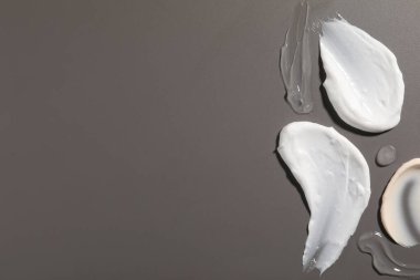 Gri arka planda farklı kozmetik ürünlerinden örnekler. Metin için boşluk