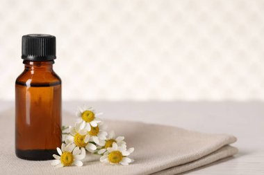 Masada bir şişe yağ ve papatya çiçeği var. Metin için boşluk