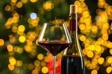 Bulanık Noel ışıklarına karşı şişe ve bardak kırmızı şarap, yakın plan. Bokeh etkisi